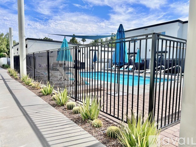 A pool surrounded by a black fence with blue umbrellas.