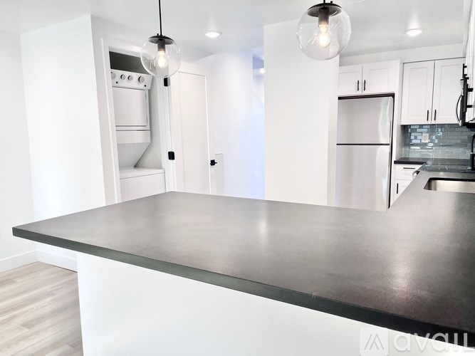 A modern kitchen with a black countertop and white cabinets.