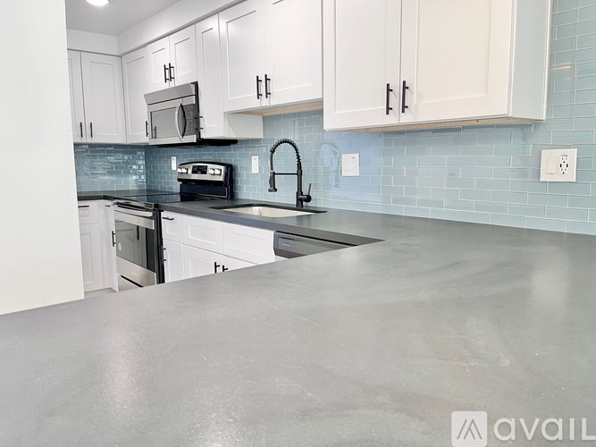 A kitchen with white cabinets and a black countertop.