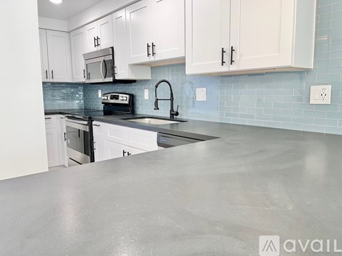 A kitchen with white cabinets and a black countertop.