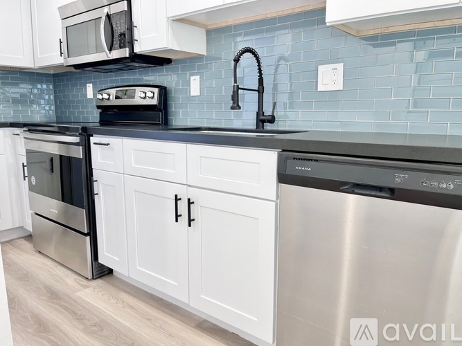 A kitchen with white cabinets and a black countertop.