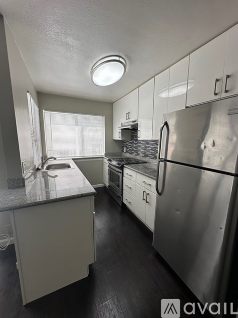 A kitchen with a stainless steel refrigerator and a countertop with a sink.