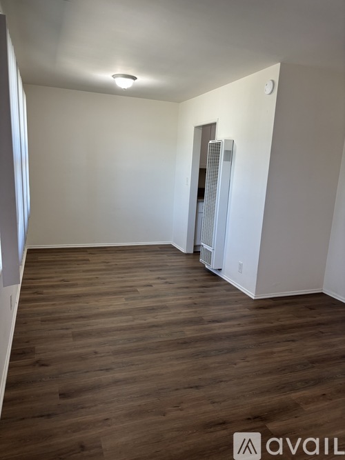 A room with wooden flooring and a white wall with a door.