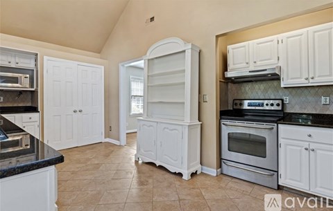 A kitchen with white cabinets and a black countertop.