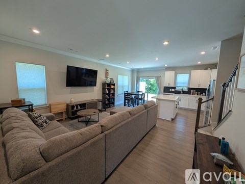 A living room with a long couch and a television on the wall.