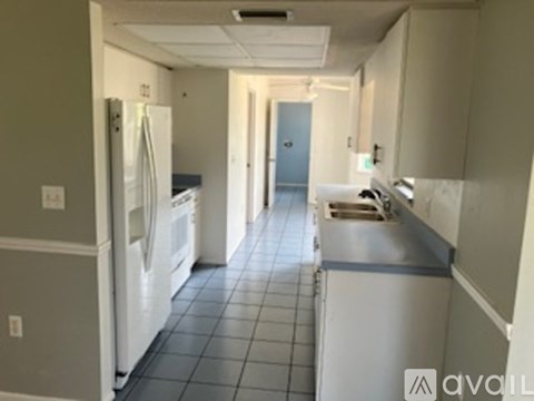 A kitchen with white appliances and a blue door.