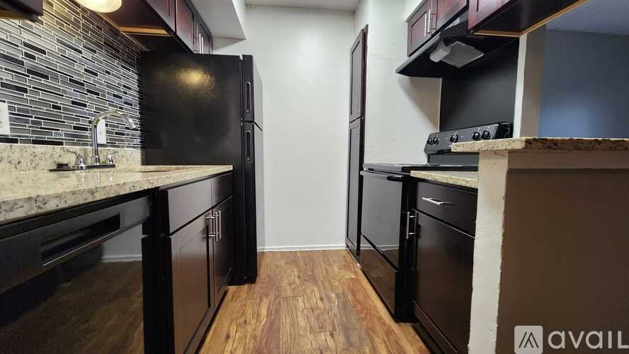 A kitchen with black appliances and wooden floors.