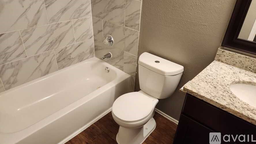 A white toilet sits next to a bathtub in a bathroom.