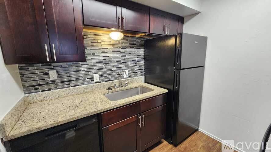 A kitchen with dark wood cabinets and a black refrigerator.