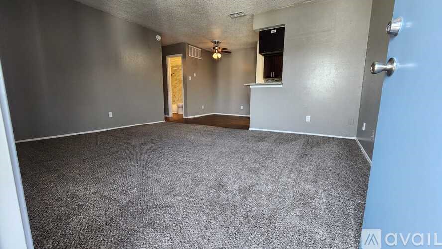 A spacious room with grey carpeting and a ceiling fan.