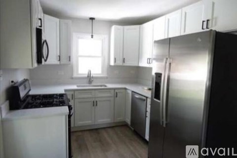 A kitchen with white cabinets and a black refrigerator.