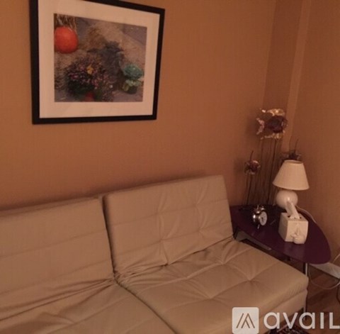 A living room with a couch, a lamp, and a picture on the wall.