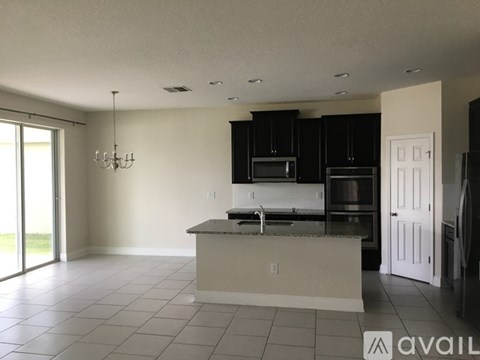 A kitchen with black cabinets and a white island.