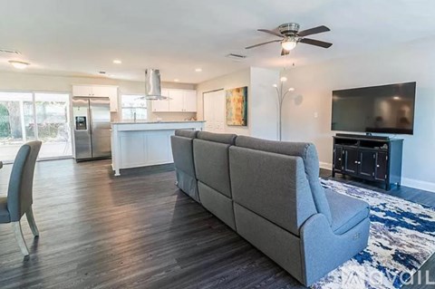A living room with a grey couch and a ceiling fan.