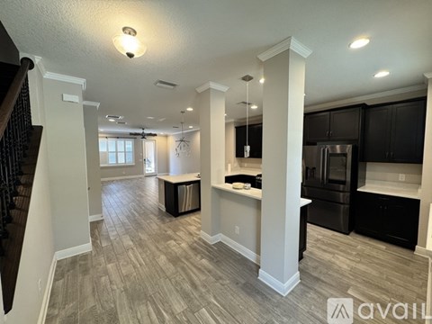 A spacious kitchen with black cabinets and a stainless steel refrigerator.