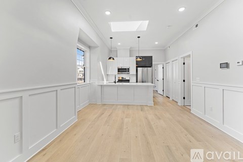 A spacious kitchen with white cabinets and a wooden floor.