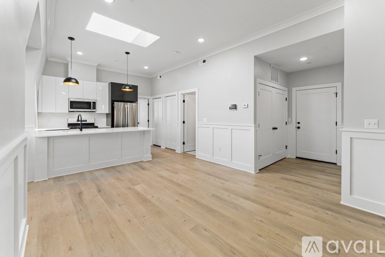 A spacious kitchen with white cabinets and a wooden floor.