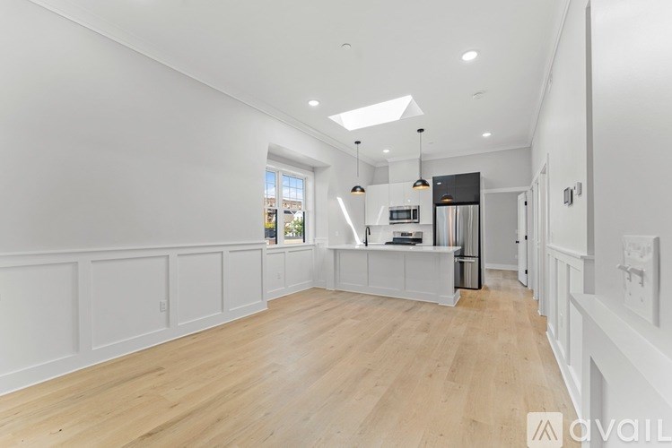 A spacious room with wooden flooring and white walls.