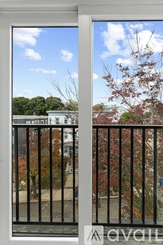A view from a balcony looking out at a tree and buildings.