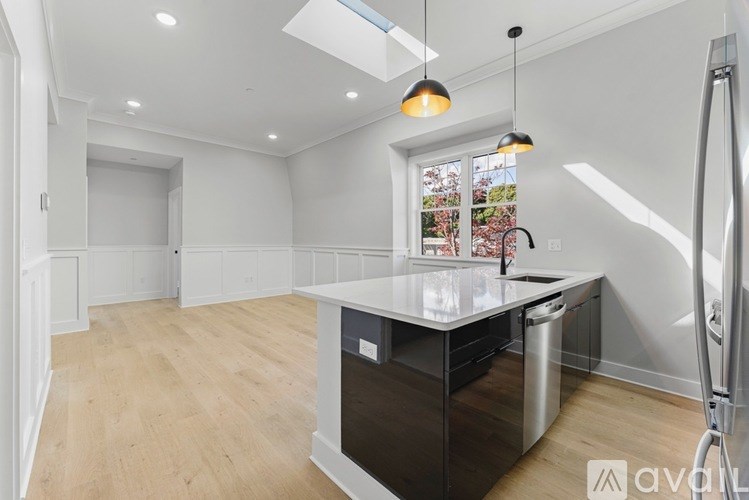 A kitchen with a white countertop and a window with a view of a garden.