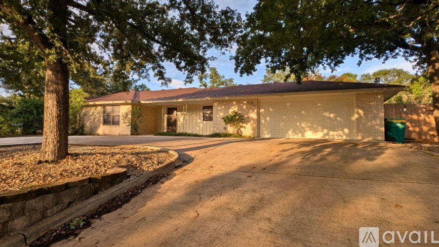 A house with a driveway and a tree in front of it.