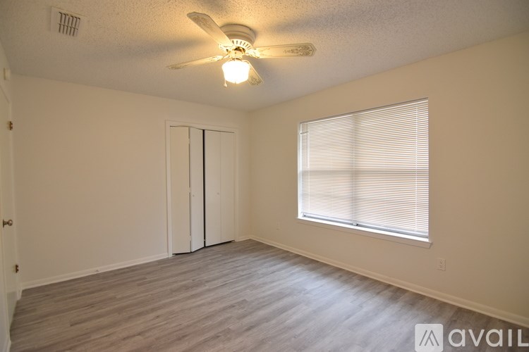 A room with a ceiling fan and a window with blinds.