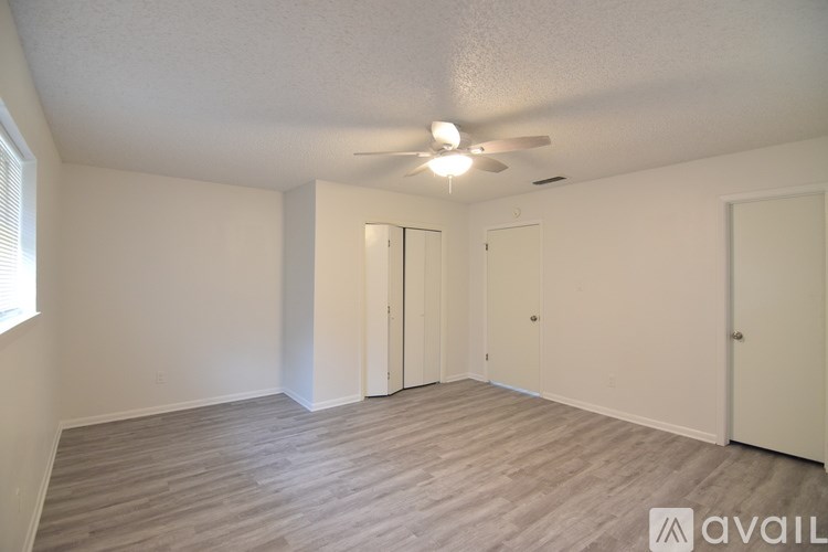 A room with a ceiling fan and wooden flooring.
