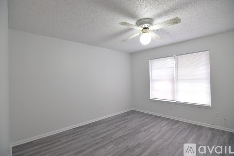 A room with a ceiling fan and a window with blinds.