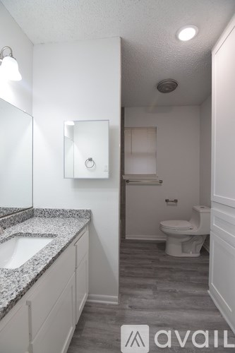 A bathroom with a toilet, sink, and mirror.