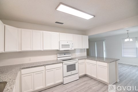 A kitchen with white cabinets and a granite countertop.