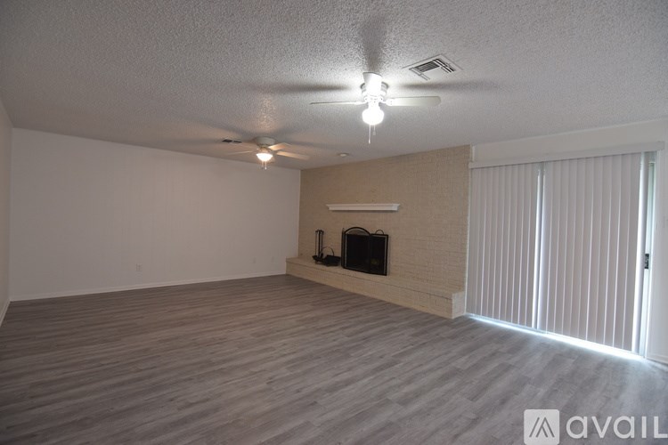 A spacious room with a fireplace and a ceiling fan.