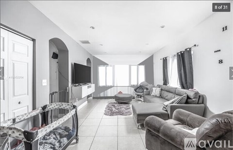 A living room with a grey couch and a television on the wall.