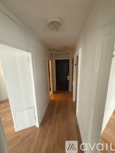 A hallway with wooden floors and white walls.