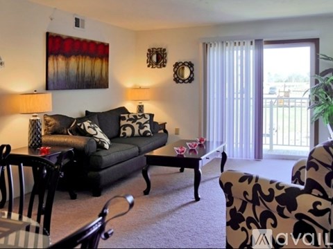 A living room with a black couch and a painting on the wall.
