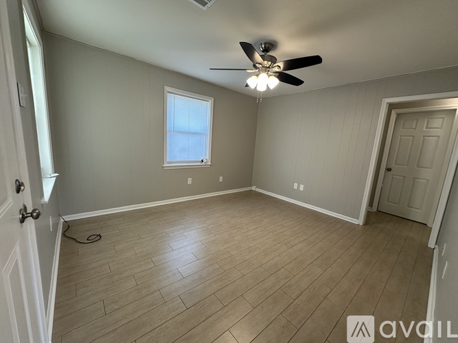 A room with a ceiling fan and wooden flooring.