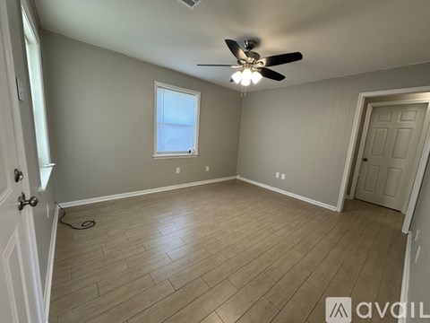 A room with a ceiling fan and wooden flooring.