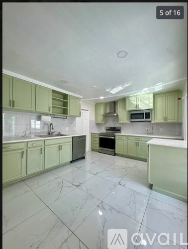 A kitchen with green cabinets and marble flooring.