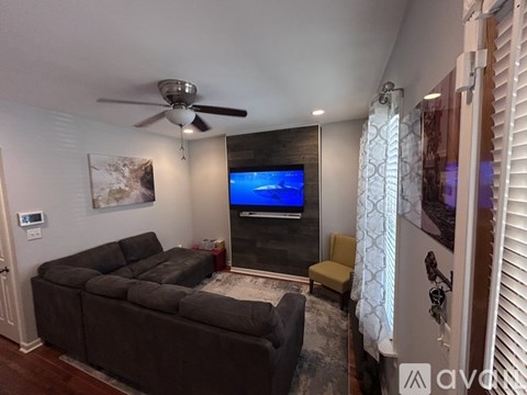 A living room with a grey couch and a flat screen TV mounted on the wall.