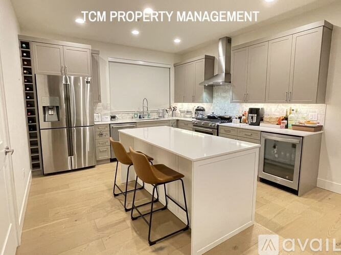 A modern kitchen with a white island and stainless steel appliances.