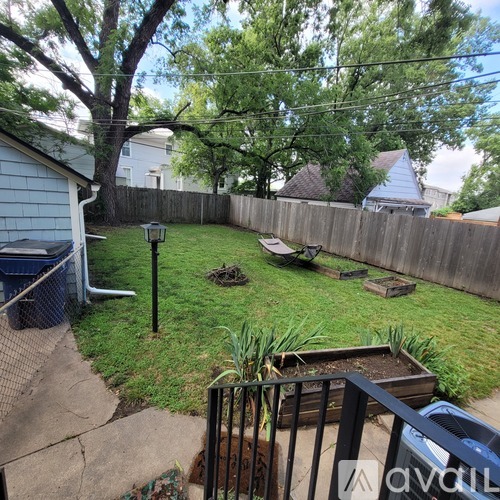 A backyard with a fence, a tree, and a small garden.
