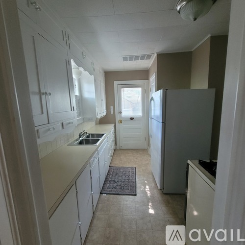 A kitchen with white cabinets and a refrigerator.