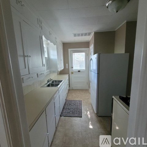A kitchen with white cabinets and a refrigerator.