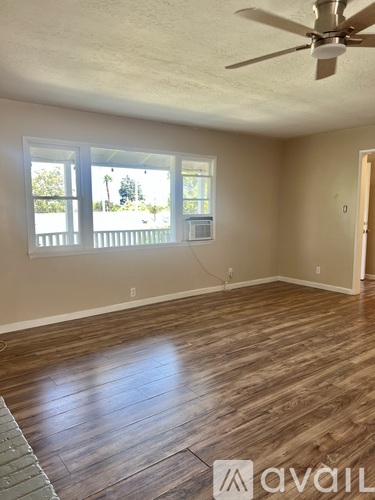 A room with a ceiling fan and wooden flooring.