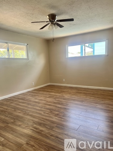 A room with a ceiling fan and two windows.