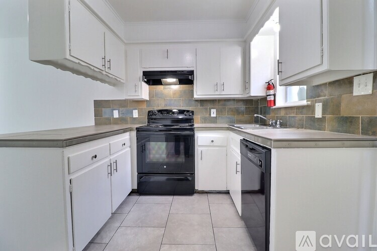 A kitchen with a stove top oven and a black dishwasher.