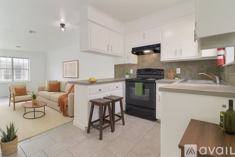 A kitchen with white cabinets and a black refrigerator.