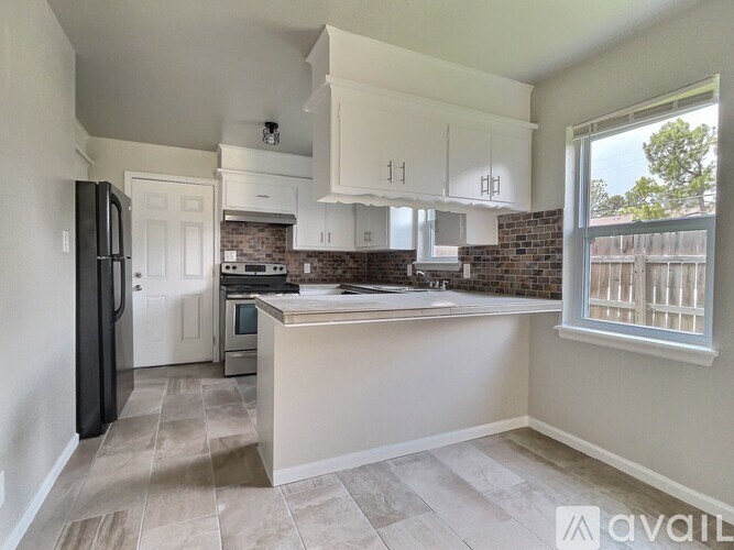A kitchen with white cabinets and a black refrigerator.