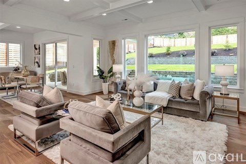 A living room with a white rug and a grey couch.