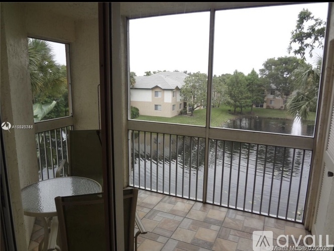 A balcony with a table and chairs overlooking a pond.