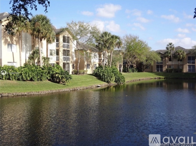 A body of water in front of a building with trees.